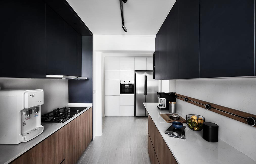 In contrast to the white laminated storage units that line the home’s entryway, the cabinets in the kitchen were clad in a combination of black and wood tones, which makes the overall space look interesting.