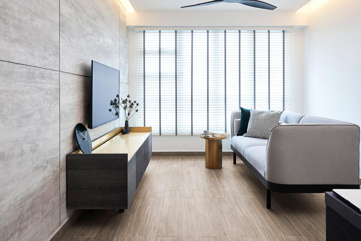 Clad in laminates with a cement screed look, the TV feature wall injects the atmosphere with a sense of rawness. The customised TV console, with its dark wood grains and gold-coloured surface, helps to pull the look together.