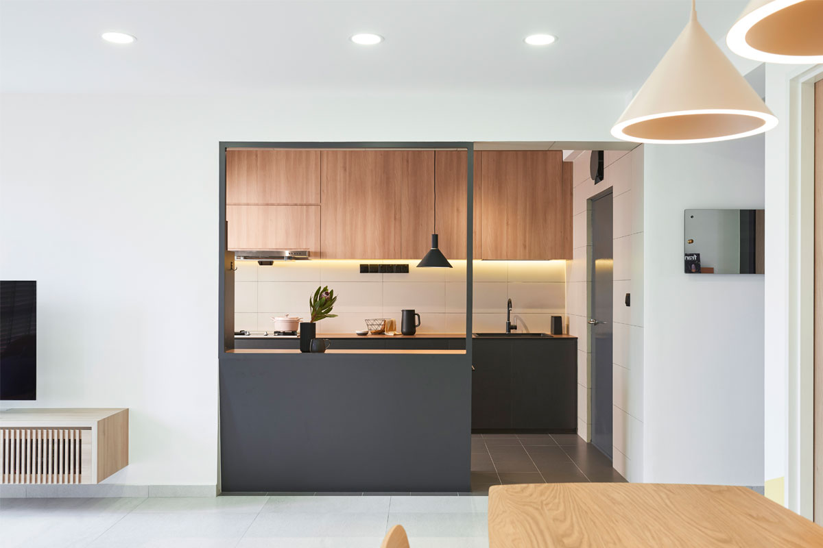 A counter with a window fronts the kitchen. Clad in dark grey, it contrasts with the rest of the space and brings it a Scandinavian touch.