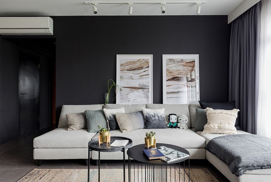 FEATURE WALL: Swathed in a coat of dark grey paint, the wall behind the sofa serves as a clean backdrop that draws focus to framed artworks hung upon it. 
