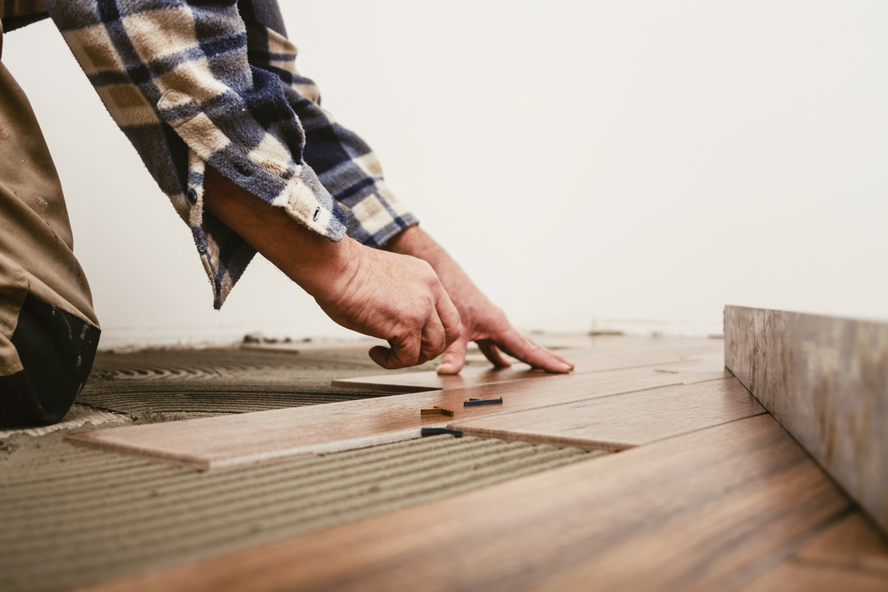 squarerooms-man-hand-placing-wooden-floorboard-on-adhesive