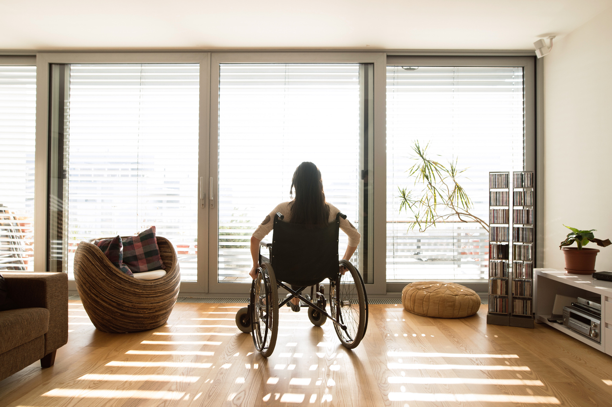 squarerooms-wheelchair-woman-living-room-window-wooden-floor