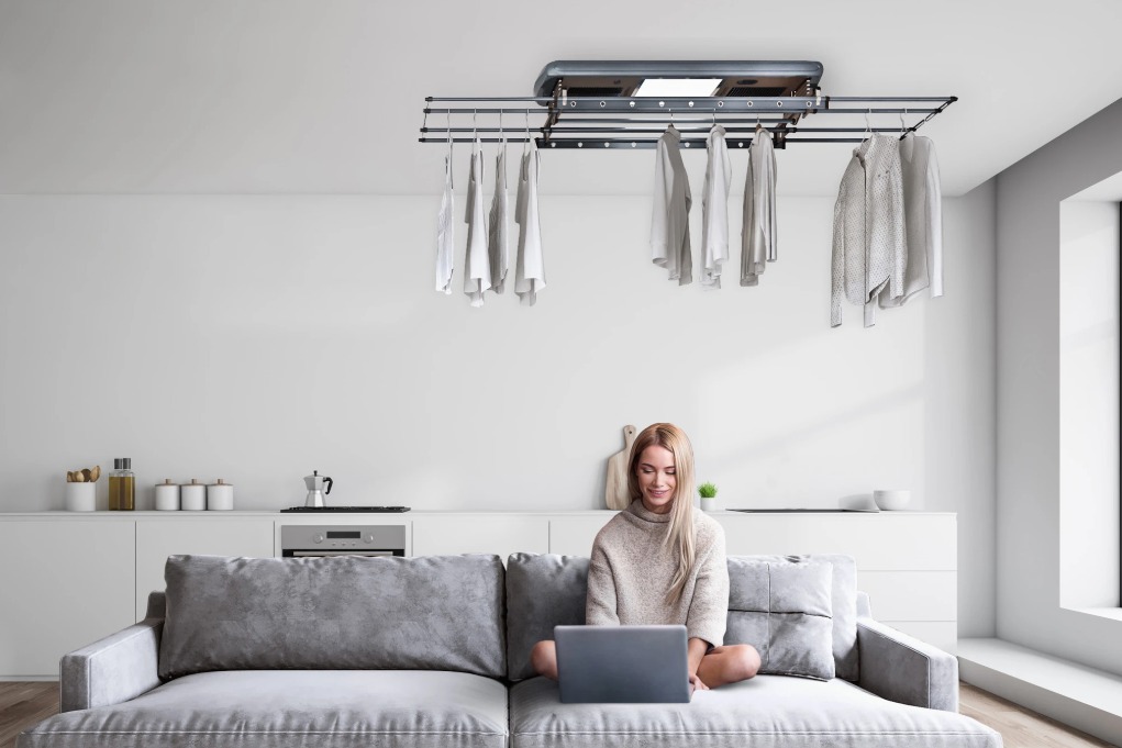 squarerooms-steigen-laundry-living-room-woman-sitting-couch-laptop-hanging-clothes-rack