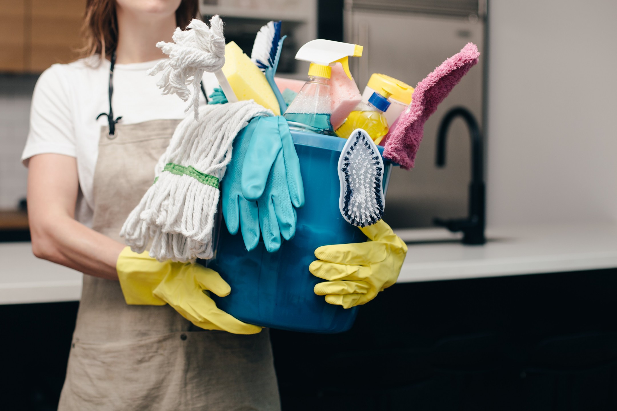 squarerooms-woman-holding-bucket-of-cleaning-supplies