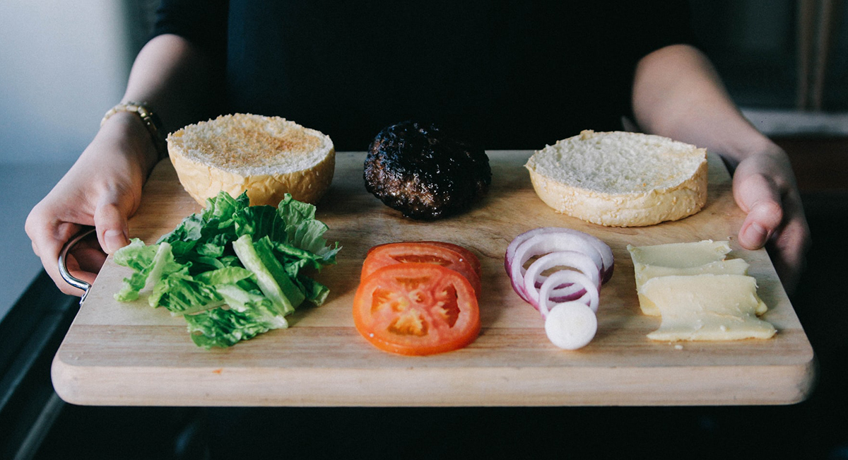 squarerooms wooden cutting chopping board woman hands holding tomato lettuce onion bread spread