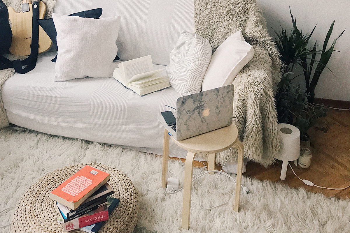 squarerooms living room cosy white couch soft rug stool laptop book pile pouf plant minimalist