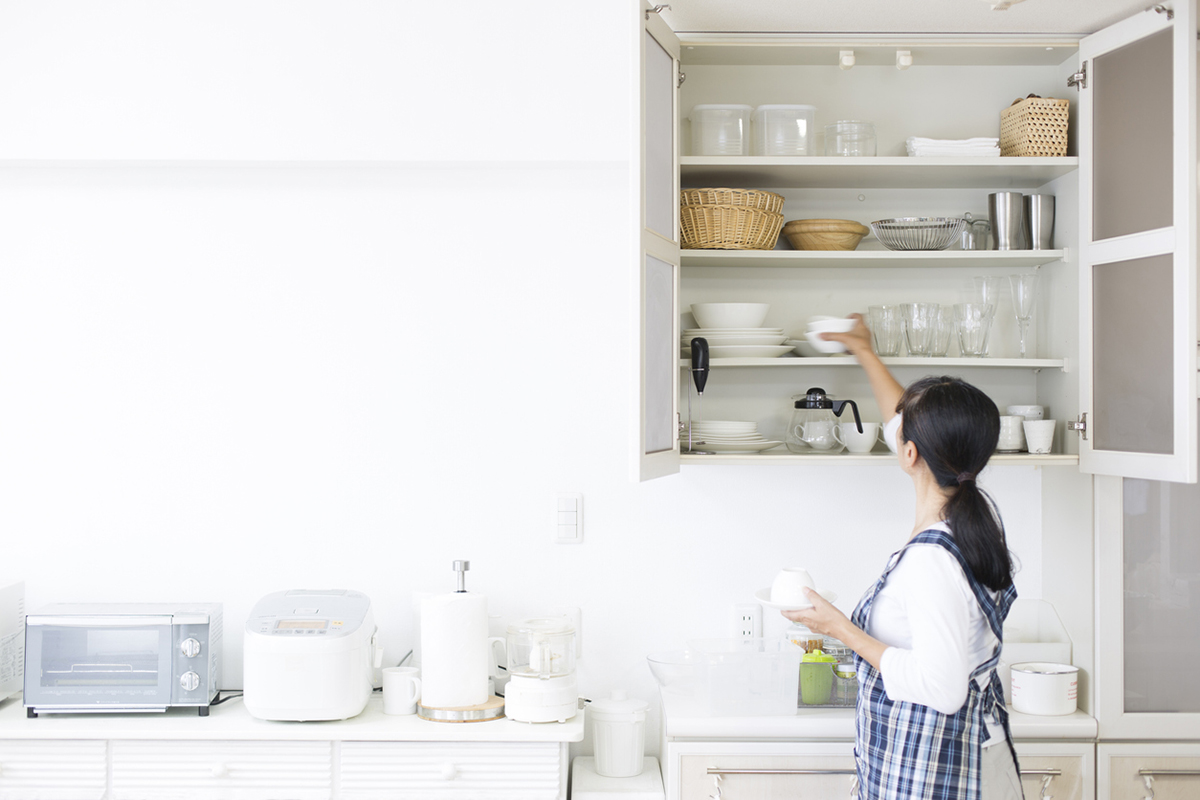 squarerooms woman opening kitchen cabinet white putting away dishes storage organisation space tidy minimalist pantry