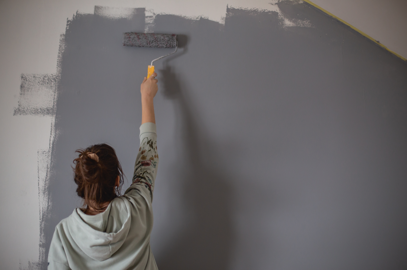 Woman painting a wall grey during renovation